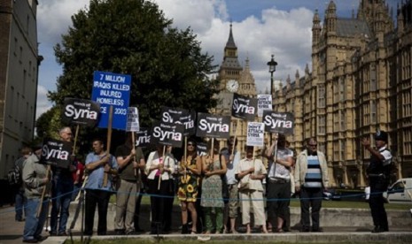 People take part in a protest calling for no military attack on Syria outside the Houses of Parliament, in London, organized by the Stop the War coalition and timed to coincide with a debate and vote by politicians, Thursday, Aug. 29, 2013. 