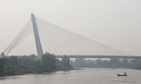 Perahu melintas di sungai Siak saat kabut asap dampak dari kebakaran hutan dan lahan kembali menyelimuti Kota Pekanbaru, Riau, Selasa (20/8/2019).