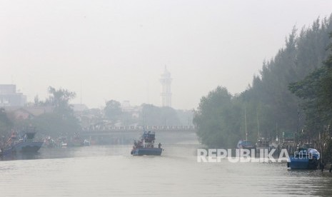 Perahu nelayan melaju menerobos kabut asap yang menyelimuti Kota di Banda Aceh, Aceh, Selasa (24/9/2019). 