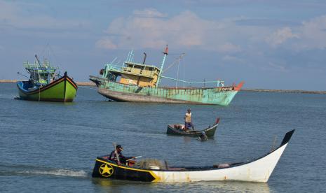 Perahu nelayan melintas dekat kapal ikan nelayan asing dengan nama KHF 1786 (kanan) yang ditangkap terkait kasus ilegal fishing di Pelabuhan Perikanan Samudera (PPS) desa Lampulo, Banda Aceh, Aceh, Selasa (14/12/2021). Kementeria Kelautan dan Perikanan (KKP) menyatakan sepanjang tahun 2021 telah menangkap lebih dari sebanyak 166 kapal pencuri ikan asal Malaysia, Vietnam , Filipina, dan kapal nelayan Indonesia terkait kasus pengunaan alat tangkap yang dilarang pukat trawl, cantrang dan tidak memiliki izin penangkapan.