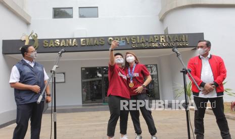 Peraih medali emas bulutangkis ganda putri Olimpiade Tokyo 2020 Greysia Polii/Apriyani Rahayu berswafoto disaksikan Gubernur DKI Jakarta Anies Baswedan (kiri) dan Ketua Umum PBSI Agung Firman Sampurna (kanan) saat peresmian Sasana Emas Greysia-Apriyani Rahayu di Gedung Multi Sport PPOP DKI Jakarta, Ragunan, Jakarta , Sabtu (14/8/2021). Pemberian nama Sasana Emas Greysia Apriyani disandangkan Anies di gedung yang sebelumnya bernama Gedung Multi Sport sebagai bentuk penghargaan atas usahanya meraih emas Olimpiade dan untuk memotivasi atlet lintas generasi. 