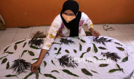 Perajin menempelkan daun pada kain saat proses pembuatan kain ecoprint di industri rumahan kawasan Kampung batik Jetis, Sidoarjo, Jawa Timur, Selasa (14/9/2021). Kerajinan kain ecoprint berbasis pewarna alam yang dibuat menjadi tas, pakaian, sepatu, dan kerudung tersebut dipasarkan secara daring dengan kisaran harga Rp100.000 hingga Rp600.000 tergantung model dan tingkat kesulitan. 