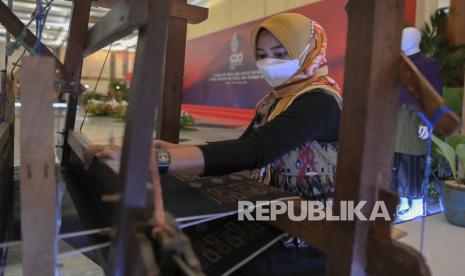 Perajin menenun kain dengan alat tenun bukan mesin (ATBM) di stan pameran produk-produk UMKM pada ajang pertemuan tingkat Menteri Keuangan dan Gubernur Bank Sentral atau Finance Ministers and Central Bank Governors Meeting (FMCBG) Presidensi G20 Indonesia di kawasan Kompleks Gelora Bung Karno, Jakarta, Jumat (18/2/2022). Pada ajang pertemuan itu Lembaga Pembiayaan Ekspor Indonesia (LPEI) memamerkan produk-produk berorientasi ekspor dari UMKM mitra binaan LPEI.