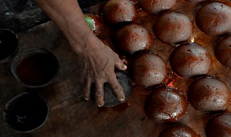 Perajin mengeluarkan gula aren dari cetakan.