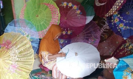 Perajin sentra payung geulis Karya Utama di Kelurahan Panyingkiran, Kecamatan Indihiang, Kota Tasikmalaya, Jawa Barat tengah mengerjakan tahap lukis, Kamis (29/9). 