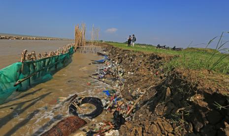 Perangkat desa melihat kondisi abrasi yang terjadi di bibir pantai desa Dadap, Juntinyuat, Indramayu, Jawa Barat, Kamis (23/6/2022). Abrasi sepanjang dua kilometer itu terjadi akibat gelombang tinggi musim angin timur dan mengancam puluhan hektar area pemukiman dan pertanian di desa itu.