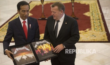 Perdana Menteri Denmark Lars Lokke Rasmussen (kanan) memberi Presiden Joko Widodo cendera mata berupa piringan hitam band Metallica usai pernyataan bersama kedua negara dalam kunjungan kerja perdana menteri Denmark di Istana Bogor, Bogor, Jawa Barat, Selasa (28/11).