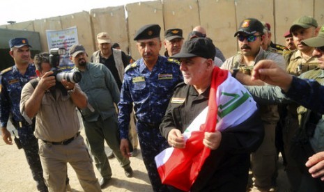 Perdana Menteri Irak Haider al-Abadi (tengah) memegang bendera nasional saat tiba di Mosul, Irak, Ahad, 9 Juli 2017. 