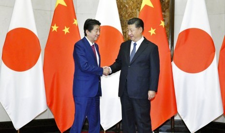 Perdana Menteri Jepang Shinzo Abe (kiri) berjabat tangan dengan Presiden Cina Xi Jinping di Diaoyutai State Guesthouse di Beijing, Cina, Jumat (26/10).