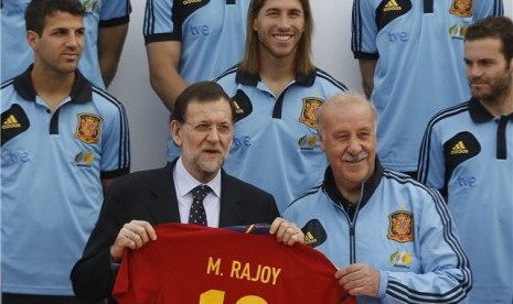 Perdana Menteri Spanyol, Mariano Rajoy (tengah), memegang replika jersey timnas Spanyol atas nama dirinya saat mengujungi pemusatan pelatihan timnas di Las Rozas, Madrid, pada Jumat (1/6). 