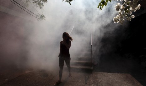 Perempuan berjalan menjauhi tempat tinggalnya yang difumigasi untuk memberantas nyamuk pembawa virus Zika dan penyakit lain yang disebabkan nyamuk di Soyapango, El Salvador, (22/1).