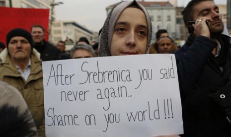 Perempuan Bosnia memegang poster berisi kecaman perang di Aleppo. Ribuan warga berkumpul di Sarajevo dalam aksi solidaritas bagi korban sipil Aleppo, Suriah, Rabu (14/12). 