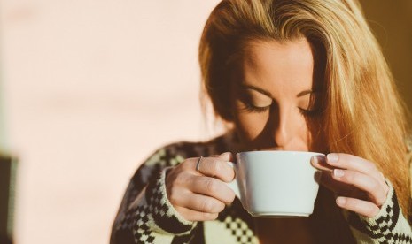 Perempuan meminum secangkir kopi.