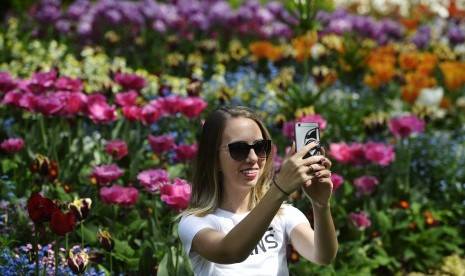 Perempuan mengambil foto dirinya dengan cara swafoto alias selfie.