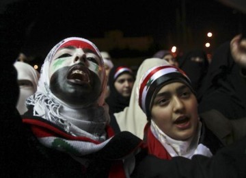 Perempuan Suriah mengecat wajah mereka dengan warna bendera Suriah dan meneriakkan slogan anti-pemerintahan Presiden Suriah Bashar Al-Asad. 