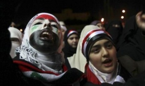 Perempuan Suriah mengecat wajah mereka dengan warna bendera Suriah dan meneriakkan slogan anti-pemerintahan Presiden Suriah Bashar Al-Asad. 