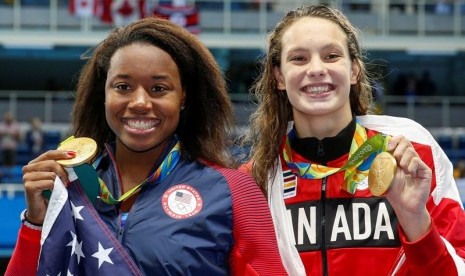 Perenang AS Simone Manuel (kiri) dan perenang Kanada Penny Oleksiak sama-sama meraih medali emas 100 meter putri di Olimpiade Rio de Janeiro.