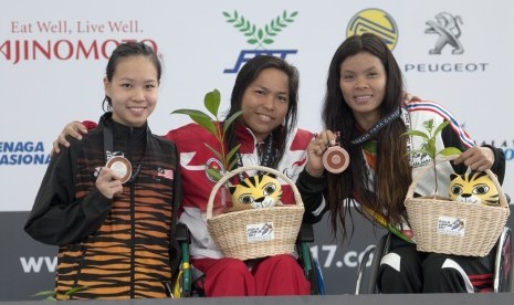 Perenang Indonesia Gusmalayanti (tengah) disamping perenang Malaysia Lim Carmen (kiri) dan perenang Thailand W Wilasini memperlihatkan medali masing-masing dalam nomor 100 meter renang gaya punggung putri Asean Para Games IX Kuala Lumpur, di National Aquatic Centre, Kuala Lumpur, Malaysia, Kames (21/9). 