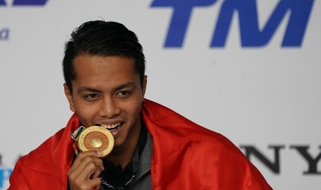 Perenang Indonesia I Gede Siman Sudartawa menggigit medali emas saat menjuarai final renang 50 meter gaya punggung putra SEA Games XXIX di National Aquatic Centre, kawasan Stadion Bukit Jalil, Kuala Lumpur, Malaysia, Senin (21/8) malam. 