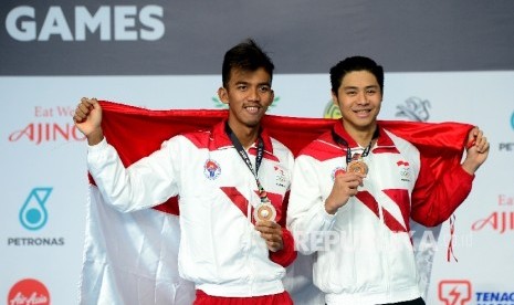 Perenang Indonesia Triady Fauzi Sidiq (kiri) bersama Glenn Victor Sutanto saat pengalungan medali cabang renang nomor 100m gaya kupu-kupu di national Aquatic, Komplek Stadion Bukit Jalil, Malaysia, Rabu (23/8).