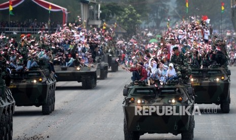 Peringatan HUT TNI ke-72. Warga menunmpang kendaraa tempur saat defile alutsista TNI pada Upacara Peringatan HUT TNI ke-72 di Dermaga Indah Kiat, Cilegon, Banten, Kamis (5/10)