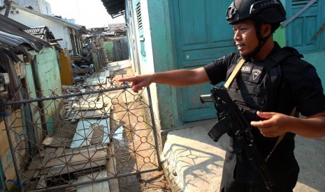 Personel Brimob berjaga di dekat lokasi rumah terduga teroris dan juga rumah warga yang rusak akibat ledakan bom bunuh diri yang dilakukan Solimah istri terduga teroris Husain alias Abu Hamzah, di Kecamatan Sibolga Sambas, Sibolga, Sumatra Utara. 