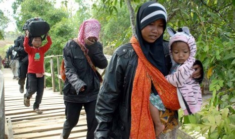   Personel Brimob mengawal sejumlah perempuan dan anak-anak, ketika berlangsungnya evakuasi dari tempat persembunyian mereka, di Desa Karanggayam dan Desa Bluuran, Sampang, Jatim, Senin (27/8). (Saiful Bahri/Antara)