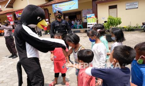 Personel detasemen Gegana berpakaian maskot walet hitam menghibur anak-anak pengungsi saat penyaluran bantuan bagi pengungsi di tempat pengungsian Merapi Desa Deyangan, Magelang, Jateng, Sabtu (21/11/2020). Detasemen Gegana Satuan Brimob Polda Jateng memberikan bantuan bagi pengungsi Merapi berupa makanan, pakaian, mainan anak dan keperluan sehari-hari. 