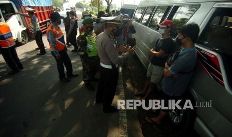 Personel kepolisian memberikan penjelasan tentang pelanggaran yang dilakukan supir travel gelap saat pengetatan mudik di jalur Selatan Tegal-Purwokerto, Klonengan, Kabupaten Tegal, Jawa Tengah, Ahad (2/5/2021). Pengetatan jalur mudik oleh Satlantas Polres Tegal tersebut mengamankan delapan mobil travel gelap yang membawa penumpang dari Jakarta dan memutar balik puluhan kendaraan pribadi pemudik awal terkait larangan mudik oleh pemerintah. 