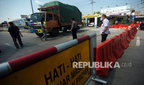 Personel kepolisian mengarahkan kendaraan untuk memutar balik saat penyekatan di pintu keluar Tol Adiwerna, Tegal, Jawa Tengah, Rabu (7/7/2021). Satlantas Polres Tegal melakukan operasi penyekatan kendaraan pintu keluar Tol Tegal dengan pemeriksaan kelengkapan surat melintas luar kota sesuai aturan PPKM Darurat Jawa-Bali guna menekan lonjakan kasus COVID-19.