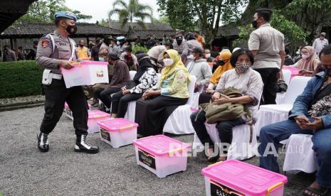 Personel polisi menyerahkan bantuan sembako kepada warga peserta vaksinasi COVID-19 di museum Kapal kompleks Taman Wisata Candi (TWC) Borobudur, Magelang, Jawa Tengah, Jumat (18/2/2022). Bantuan sembako bagi pelaku wisata dan seniman di sekitar kawasan Borobudur sebagai wujud kepedulian Polri kepada masyarakat yang terdampak pandemi Covid-19. Pemprov Jateng juga mendorong para pelaku wisata untuk disuntik vaksinasi penguat.