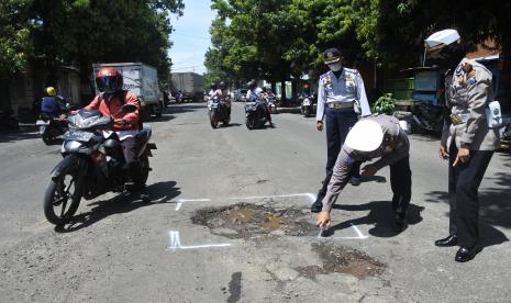 Personel Satlantas dan Dinas Perhubungan menandai jalan yang berlubang dan rusak (ilustrasi) 