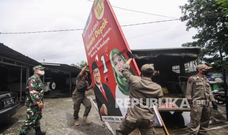 Personel Satpol PP bersama anggota TNI menertibkan APK Pilkada Calon Wali Kota Depok di Cimanggis, Depok, Jawa Barat, Senin (7/12/2020). Penertiban Alat Peraga Kampanye (APK) tersebut dilakukan karena telah memasuki masa tenang Pilkada Serentak hingga 8 Desember 2020.