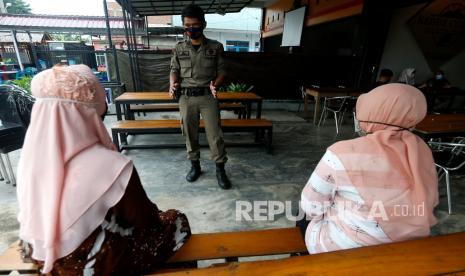 Personel Satpol PP yang tergabung dalam tim gugus tugas percepatan penanganan COVID-19 Ulee Kareng memberikan pengarahan kepada pengunjung warung kopi (warkop) untuk memakai masker dan jaga jarak saat razia penertiban protokol kesehatan di Banda Aceh, Aceh, Sabtu (12/9/2020). Tim gugus tugas percepatan penanganan COVID-19 Kota Banda Aceh kembali meningkatkan sosialisasi dan memberikan peringatan kepada tempat usaha yang mengabaikan protokol kesehatan sebagai upaya mencegah penyebaran serta penularan yang terus meningkat di daerah itu. 