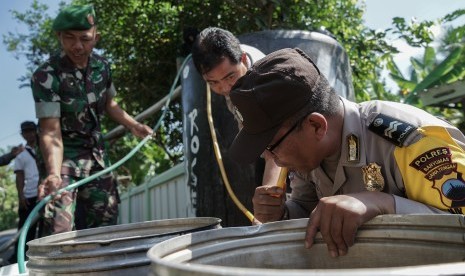 Personel TNI dan Polri membantu mengalirkan air dari bak penampungan ke ember warga saat pembagian air bersih oleh Polres Banyumas, di Desa Kediri, Karanglewas, Banyumas, Jateng, Jumat (21/6/2019). Ratusan hektar sawah mulai kering akibat musim kemarau di Kabupaten Banyumas, dan BPBD Kabupaten Banyumas melakukan antisipasi dengan menyalurkan 65.000 liter air bersih kepada warga untuk mengantisipasi kekeringan yang terus meluas.