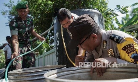 Personel TNI dan Polri membantu mengalirkan air dari bak penampungan ke ember warga saat pembagian air bersih.