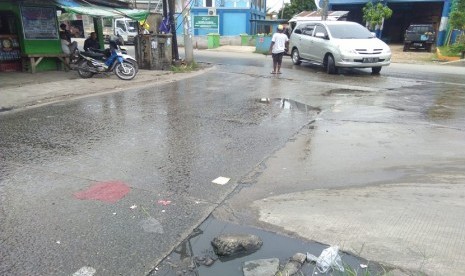 Pertigaan Jalan Raya Papan Mas arah Flyover Pasar Tambun, Kabupaten Bekasi kondisinya tergenang air selokan yang mampet.