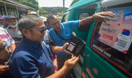 Perwakilan Organda menunjukkan cara memindai kode QY untuk pembayaran nontunai angkutan kota kepada supirdi Padang, Sumatera Barat, Selasa (14/6/2022).Pemkot Padang bekerja sama dengan Organda dan BRI menerapkan pembayaran nontunai bagi warga kota pengguna angkot melalui aplikasi Quick Response Code Indonesian Standard (QRIS).