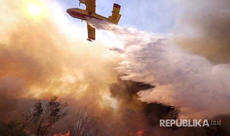 Pesawat pembom air berusaha memadamkan api di jalan Ronald Reagan, Simmi Valley, Kalifornia (12/11) waktu setempat.