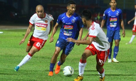 Pesepak bola Arema FC Dendy santosa (tengah) berusaha melewati hadangan pesepak bola Perseru Badak Lampung FC Syahrul Mustofa (kanan) dan Marcus Vinicius Vidal Cunha (kiri) dalam pertandingan Liga I di Stadion Kanjuruhan, Malang, Jawa Timur, Selasa (16/7/2019). 