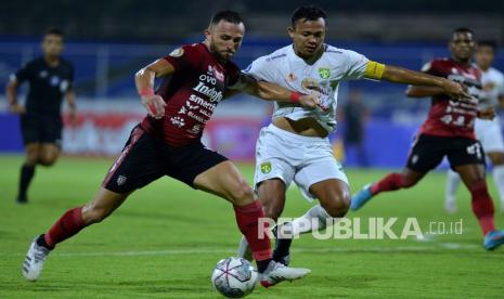 Pesepak bola Bali United Ilija Spasojevic (kiri) berebut bola dengan pesepak bola Persebaya Surabaya Arif Satria (kanan) saat pertandingan Liga 1 di Stadion I Gusti Ngurah Rai, Denpasar, Bali, Jumat (25/3/2022). 