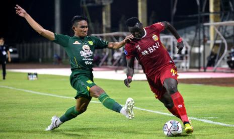 Pesepak bola Bhayangkara FC Ezechiel Ndouasel (kanan) berebut bola dengan pesepak bola Persebaya Surabaya Rizky Ridho (kiri) saat pertandingan Liga 1 di Stadion I Gusti Ngurah Rai, Denpasar, Bali, Selasa (18/1/2022).  Bhayangkara FC unggul 2-1 di laga tersebut.