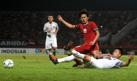 Pesepak bola Indonesia U-19 Hanis Saghara Putra (kiri) berebut bola dengan pesepak bola Vietnam U-19 dalam laga penyisihan grup A Piala AFF U19 Dang Van Toi (kanan) di Gelora Delta Sidoarjo, Sidoarjo, Jawa Timur, Sabtu (7/7). 