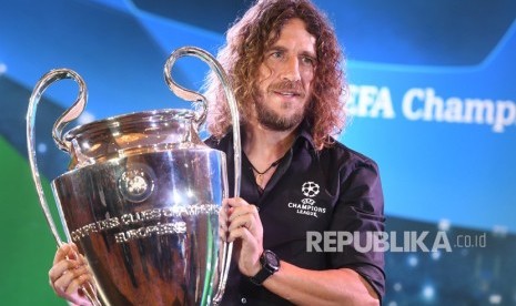 Pesepak bola legenda FC Barcelona Carles Puyol mengangkat trofi Liga Champions saat UEFA Champions League Trophy Tour digelar di Surabaya, Jawa Timur, Rabu (13/3/2019). 