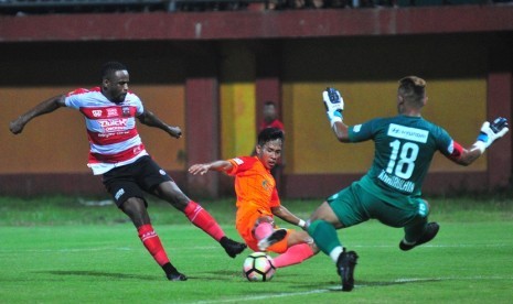 Pesepak bola Madura United (MU) Greg Nwokolo (kiri) berebut bola dengan pesepak bola Hougang United Singapura Moh Nazrul Nazari (tengah) dan Khairudin Khalid (kanan) dalam laga uji coba internasional di Stadion Gelora Ratu Pamelingan (SGRP) Pamekasan, Jawa Timur, Minggu (4/3).