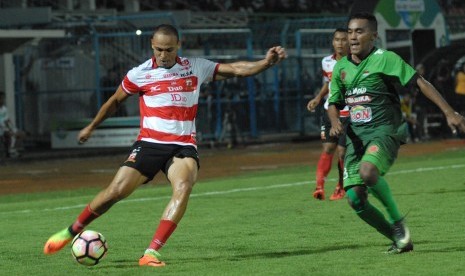 Pesepak bola Madura United (MU) Piter Osaze Odem Wingie (kiri) dibayangi pesepak bola PS TNI Mohammad Kasim Slamat (kanan) berusaha menendang bola dalam pertandingan kompetisi Liga 1 di Stadion Gelora Bangkalan, Bangkalan, Jawa Timur, Jumat (19/5).