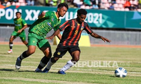 Pesepak bola Papua M Arody Uopdana (kanan) berebut bola dengan pesepak bola Kalimantan Timur Pusam Wahyu Ramadhan (kiri) saat pertandingan Semi Final Sepak Bola Putra PON Papua di Stadion Mandala, Kota Jayapura, Papua, Selasa (12/10). 