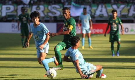 Pesepak bola Persebaya Ruben Karel Sanadi (tengah) mencoba melewati hadangan pesepak bola Persela Kei Hirose (kiri) dan Ahmad Subagja Baasith (kanan) pada pertandingan Liga 1 2019 di Stadion Gelora Bung Tomo, Surabaya, Jawa Timur, Senin (1/7/2019). 