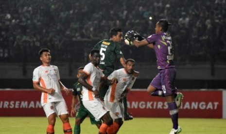 Pesepak bola Persebaya Surabaya Otavio Dutra (ketiga kiri) menyundul bola yang berusaha ditahan penjaga gawang Perseru Serui Annas Fitranto (kanan) dalam kompetisi Liga 1 di Stadion Gelora Bung Tomo (GBT) Surabaya, Jawa Timur, Ahad (25/3). Persebaya Surabaya menang atas Perseru Serui dengan skor 1-0. 