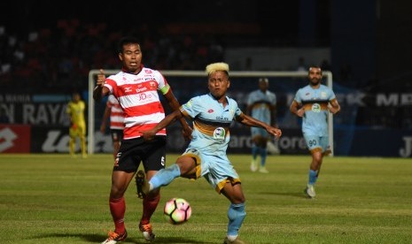 Pesepak bola Persela Lamongan Moch. Fahmi Al-Ayyubi (kanan) berebut bola dengan pesepak bola Madura United FC Munhar (kiri) dalam pertandingan Gojek Traveloka Liga 1 di Stadion Surajaya Lamongan, Jawa Timur, Jumat (21/4). 